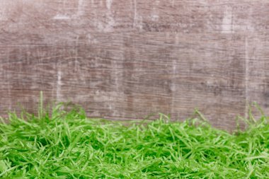 Ahşap arka plan önünde güzel yeşil çim. Paskalya tebrik kartı. Kopya alanı metin için.