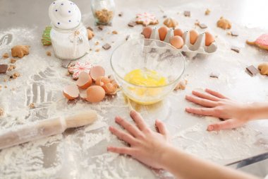 Erkek, kurabiye pişirme için hazırlık. Hamur, yumurta, yumurta kabuğu ve mutfak masasının üzerinde bisküvi ile un.