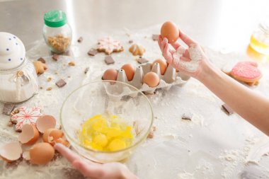 female baking cookies, preparation for baking. Flour with dough, eggs, eggshells, and biscuits on the kitchen table. clipart
