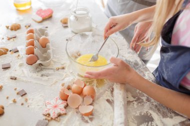 kadın ve kız, kurabiye pişirme için hazırlık. erkek aşçı tatlılar eller. Hamur, yumurta, yumurta kabuğu ve mutfak masasının üzerinde bisküvi ile un.