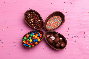 Çikolata Paskalya yumurtaları ve parlak pembe bir arka plan üzerinde renkli şekerler. Paskalya tatlı kavramı.