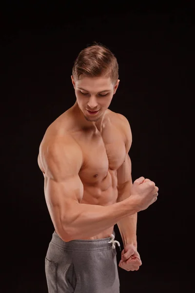 有完美肌肉和姿势的运动员 一个健美运动员 在黑色的背景下显示二头肌和三肱 健身房 建立肌肉概念 — 图库照片