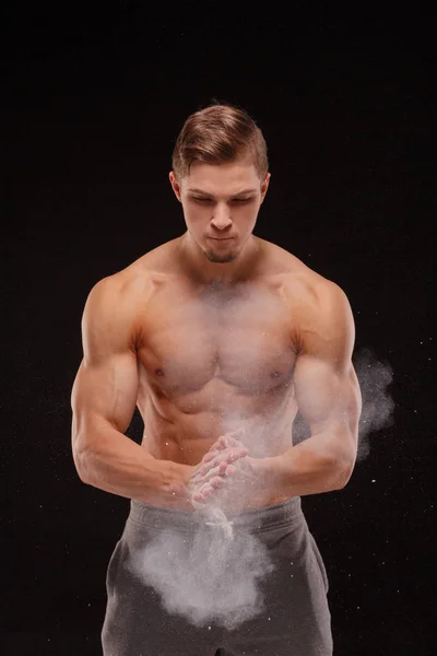 英俊的运动员与完美的身体在锻炼前用白色粉末涂抹双手 — 图库照片