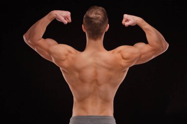 Seksi bir vücut-builder siyah bir arka plan. Bir atlet dramatik portresi. Kurutma. Yardım ve vücudun heykel kas. Sağlıklı yaşam konsepti. Omuz ve sırt kaslarının.