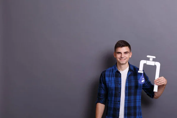 Jovem Segurando Imagem Torneira Com Gota Água Fundo Cinza Conceito — Fotografia de Stock