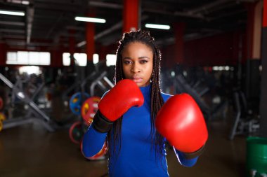 Afrikalı güzel kadın boksör kırmızı eldiven giymiş bir spor salonunda eğitiyor.
