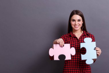 Renkli bir Yapboz parçalarını gri bir arka plan üzerinde gösterilen bir genç kız. Başarı çözme sorunlar kavramı.