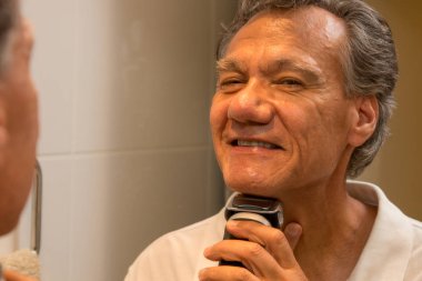 Elektrikli tıraş makinesi ya da tıraş makinesiyle tıraş olan bir adam.