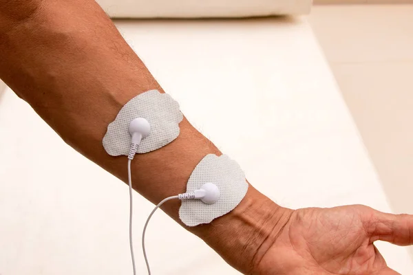 Patient using a Home Electrical Nerve Stimulation Unit also Known as TENS Unit on his Body