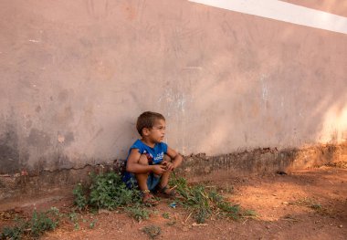 Planaltina, Gois, Brezilya-21 Nisan 2018: Yoksul Planaltina kentindeki evinin önünde oturan küçük bir çocuk