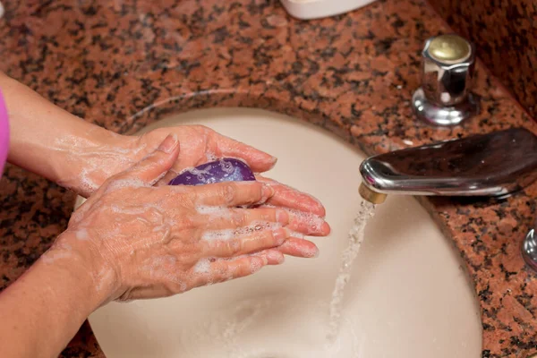 Ellerini sabun ve lavaboda suyla yıkayan kadın