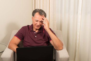 Adam evde dizüstü bilgisayarıyla çalışıyor. 