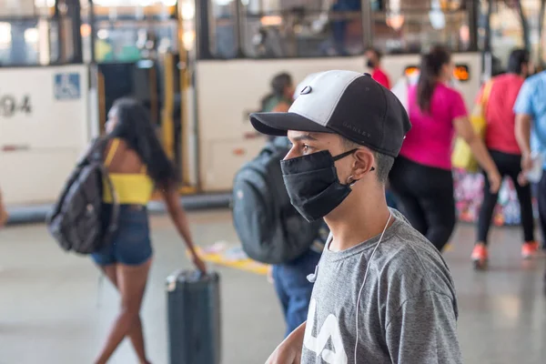 Brezilya, 28 Nisan 2020: Şehir merkezindeki otobüs durağında koruyucu maske takan genç adam