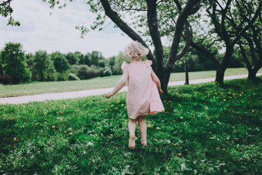 Küçük kız çimenlerde koşuyor..