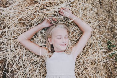 Bir kız bir saman üzerinde yatıyor.