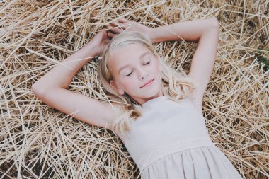 Bir kız bir saman üzerinde yatıyor.