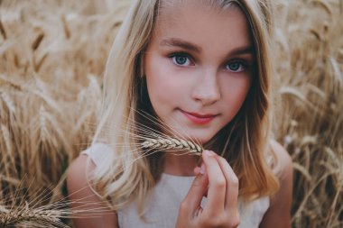 Bir buğday alanında güzel gülümseyen kız.