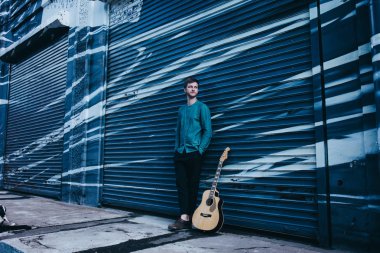 Yenilikçi müzisyen bir gitarla duruyor. 