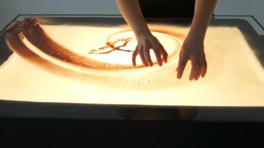 Kum ile çizim. Kum üzerinde beyaz bir ekrana çizme. Kum sanatçı. Eller berabere