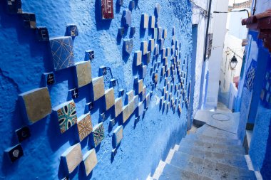 Fas 'ın eski Chefchaouen şehrinde mavi ve beyaz renklerle süslenmiş dar bir cadde..