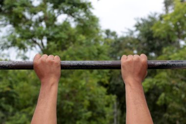 Doğa arka plan ile egzersiz için yatay çubuğu çekme yapan güçlü erkek kol