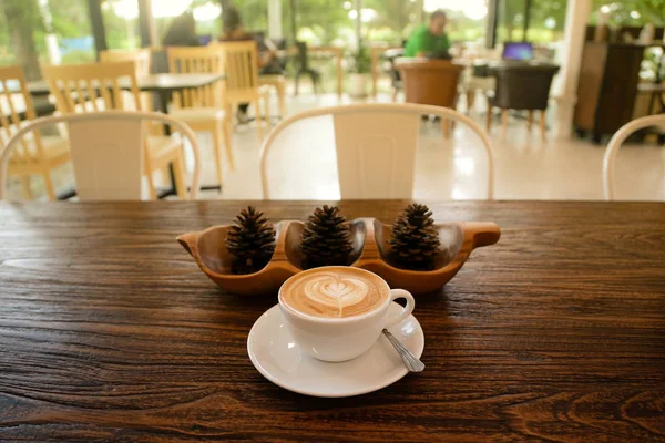 Taza de café caliente con conos de pino en la mesa de madera en la cafetería — Foto de Stock