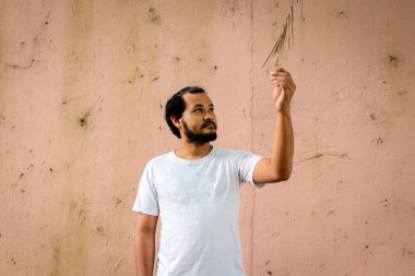 Asya adam tutun ve dik dik kuru yaprakları ile eski duvarlar arka plan olarak var.