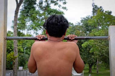 Doğa arka planda yatay çubuğu Çekme ile egzersiz yaparak güçlü bir adam