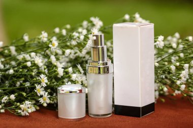 Cilt kremi ve bir ahşap masa ve arka plan bulanık bir güzel çiçekler ile kozmetik kutusu