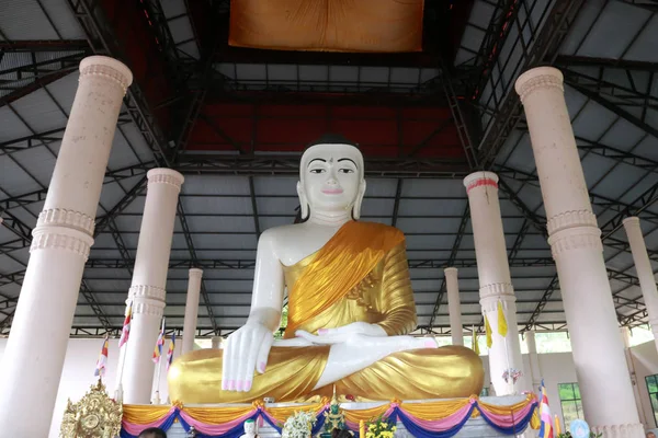 Antique white Buddha statue covered in golden yellow robes at temple in Myanmar. — Stock Photo, Image