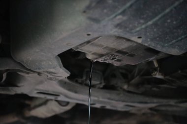 Old and dirty engine oil being drained from underneath a car during an engine oil change. clipart