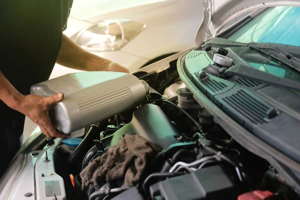 Bilmekaniker är att fylla upp motoroljan till kundernas bil i hans bilverkstad. Byta motorolja i garaget shop. — Stockfoto