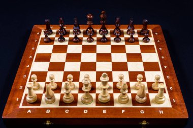 Siyah bir arka planda satranç tahtasında tahta satranç seti