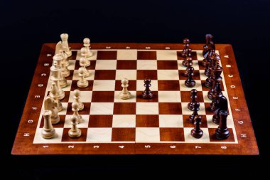 Siyah bir arka planda satranç tahtasında tahta satranç seti