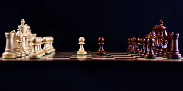 wooden chess set on a chessboard on a black background, side view.