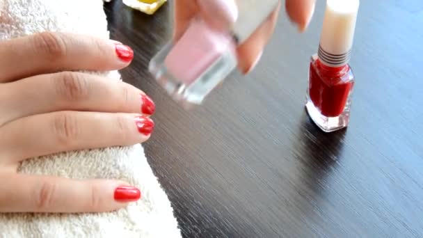 Манікюр - красиві доглянуті жіночі нігті з червоним лаком для нігтів на м'якому білому рушнику. червоний і перламутровий лак, вибирає цвях — стокове відео
