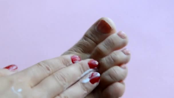 Mulher se preocupando com os pés e colocando creme hidratante nele — Vídeo de Stock