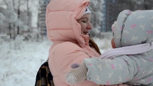 Rodzina przechadzająca się przez Winter Woodland. Dziewczynka i jej mama spacerują po zimowym lesie. Bawić się śniegiem i sankami. w ciepłych zimowych ubraniach — Wideo stockowe