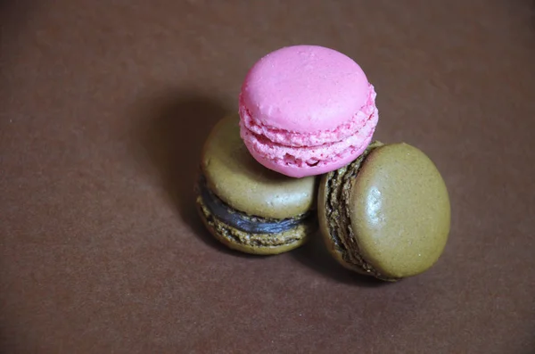 Kleurrijke smakelijke macarons op een rij. macarons van verschillende kleuren op een bruine achtergrond — Stockfoto