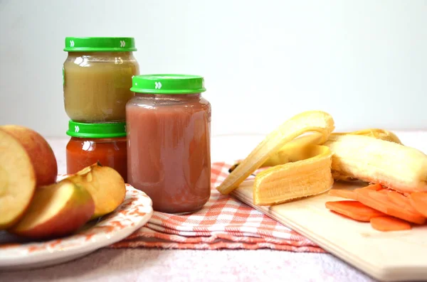 Jedzenie dla niemowląt, puree z owoców dla niemowląt w szklanym słoiku, plasterki marchwi, jabłko, banan — Zdjęcie stockowe