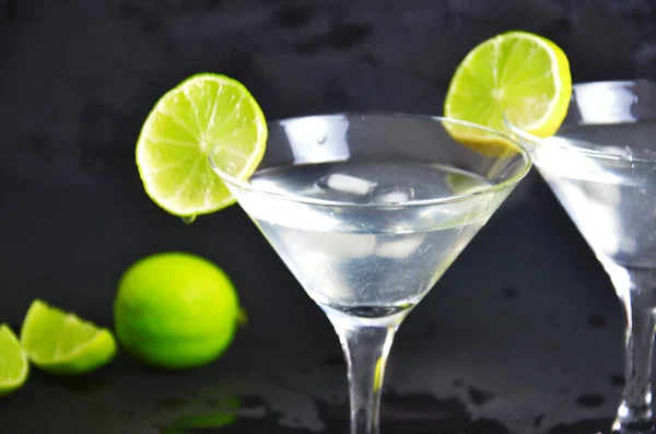 Siyah arka planda iki bardak limonlu martini. Bir barda iki bardak martini kokteyli.