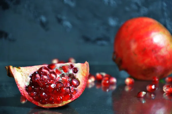 Ripe pomegranate with leaves on a black board on a dark background — Stock Photo, Image