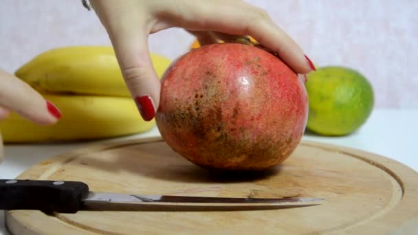 Krájí a loupá čerstvé šťavnaté červené granátové jablko pro ovocný salát. Ovoce na pozadí. Dieta, málo kalorií, vegetariánství, přírodní vitamíny. Detailní záběr ženy ručně broušené granátové jablko na palubě. Boční pohled. — Stock video
