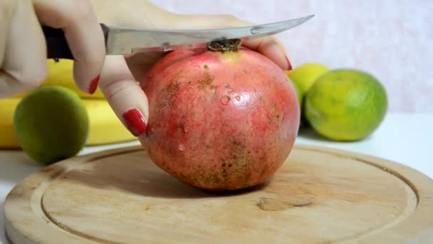 Krájí a loupá čerstvé šťavnaté červené granátové jablko pro ovocný salát. Ovoce na pozadí. Dieta, málo kalorií, vegetariánství, přírodní vitamíny. Detailní záběr ženy ručně broušené granátové jablko na palubě. Boční pohled. — Stock video
