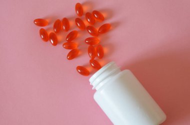 Çeşitli ilaç hapları, haplar, kapsüller ve pembe arka planda bir şişe. Metin için alanı kopyala.