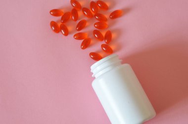 Çeşitli ilaç hapları, haplar, kapsüller ve pembe arka planda bir şişe. Metin için alanı kopyala.