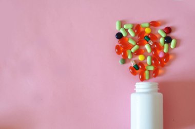 Çeşitli ilaç hapları, haplar, kapsüller ve pembe arka planda bir şişe. Metin için alanı kopyala.