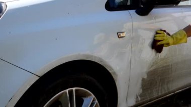 Sarı eldivenli El 'in yakın çekimi bez yıkamalı çeşitli makine parçaları fırçalayan beyaz araba