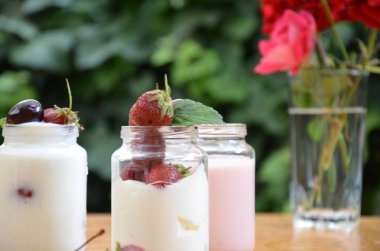 Sağlıklı kahvaltıda puding, yoğurt, granola, çilek, kiraz, hanımeli böğürtlen, fındık ve yoğurt yenir. Vejetaryen konsept yiyecekler. Üst Manzara. Arka planda puding ya da kokteyl