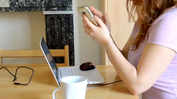 Karantina ve kendini izole etme sürecinde evden çalışan ciddi genç kadın dizüstü bilgisayarda e-posta yazıyor, internetten telefon kullanıyor, kahve ya da çay içiyor, internet üzerinden çalışan bir kadın. — Stok video